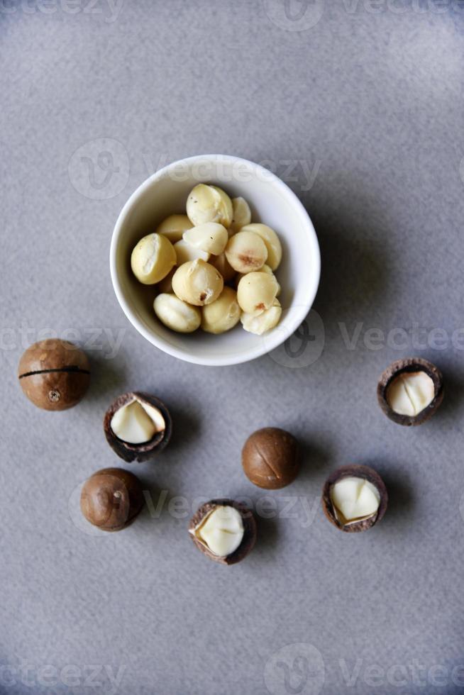 Delicious peeled Macadamia nut in a salad bowl on a gray background. The kernels of a delicious Macadamia nut close-up. photo