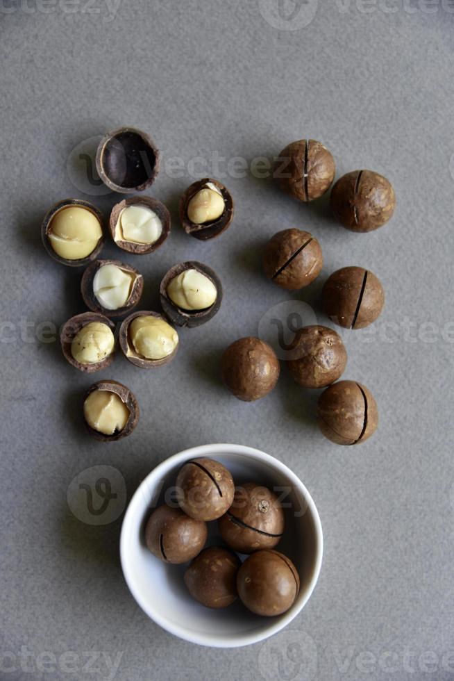 Delicious macadamia nut in a cup on a gray background. Broken nuts and shells. photo