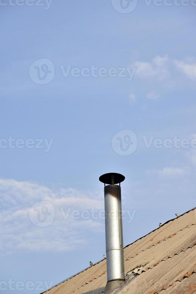 Metal chimney on the roof of an old house. Chimney chimney on the background of clouds of the sky. photo