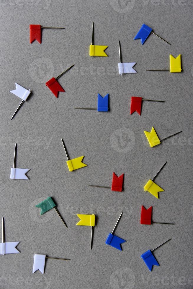 Multicolored iron paper clips on a gray background. Stationery paper fasteners scattered on a gray background like stars. photo