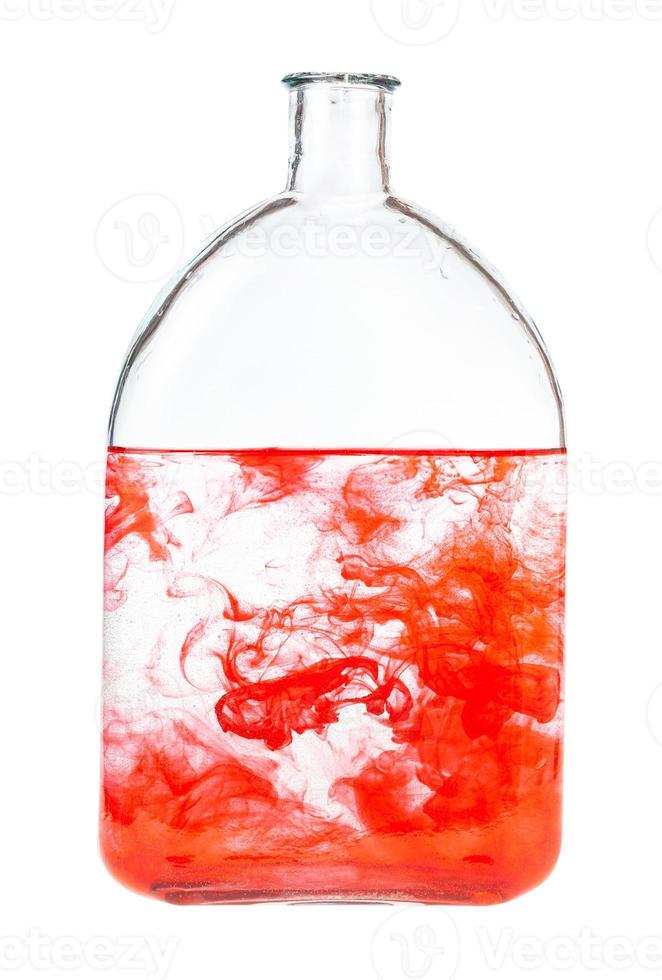 red watercolour dissolves in water in bottle photo