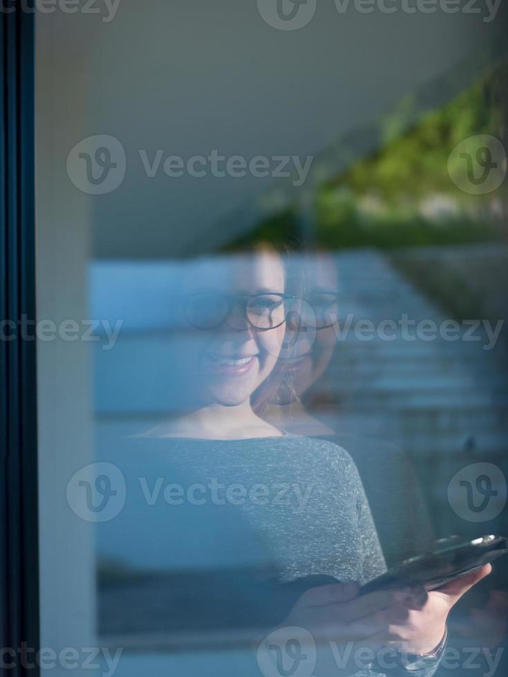 mujer usando tableta en casa junto a la ventana foto