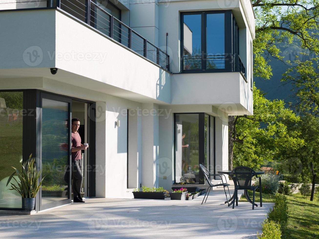 man drinking coffee in front of her luxury home villa photo