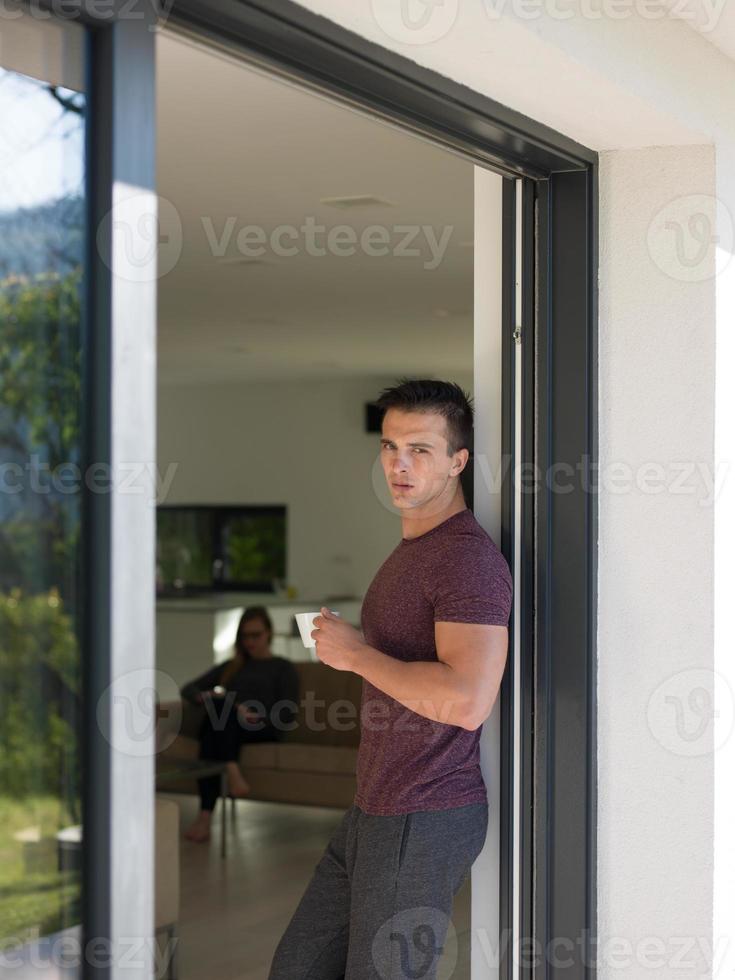 man drinking coffee in front of her luxury home villa photo