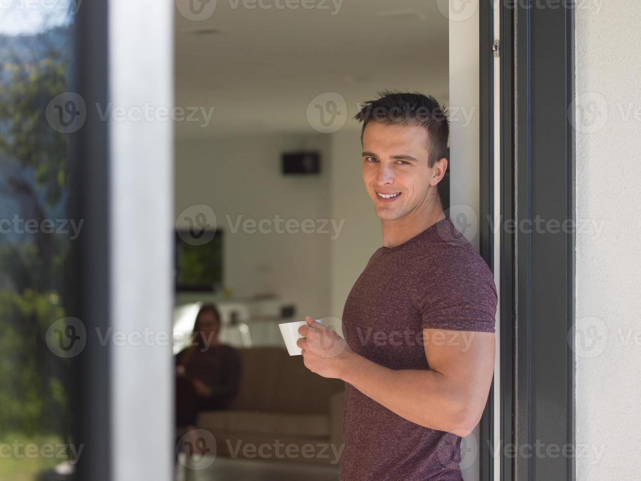 man drinking coffee in front of her luxury home villa photo