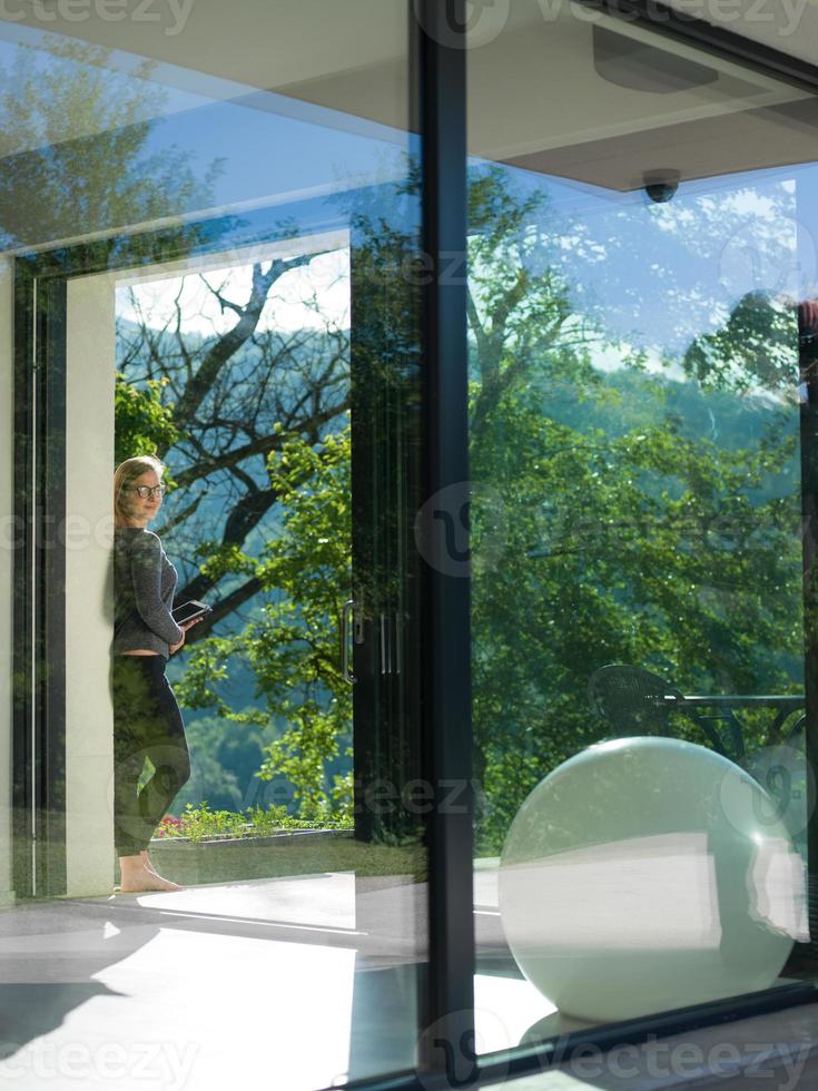 women using tablet computer in front of luxury home villa photo