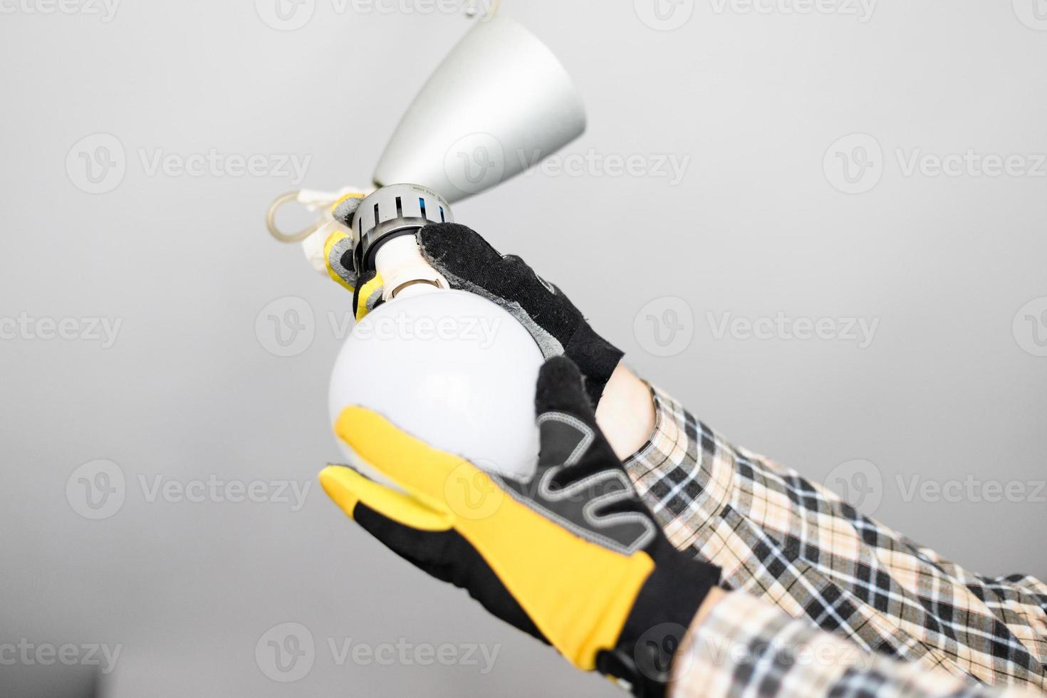 electrician removing bulb from fault ceiling light photo