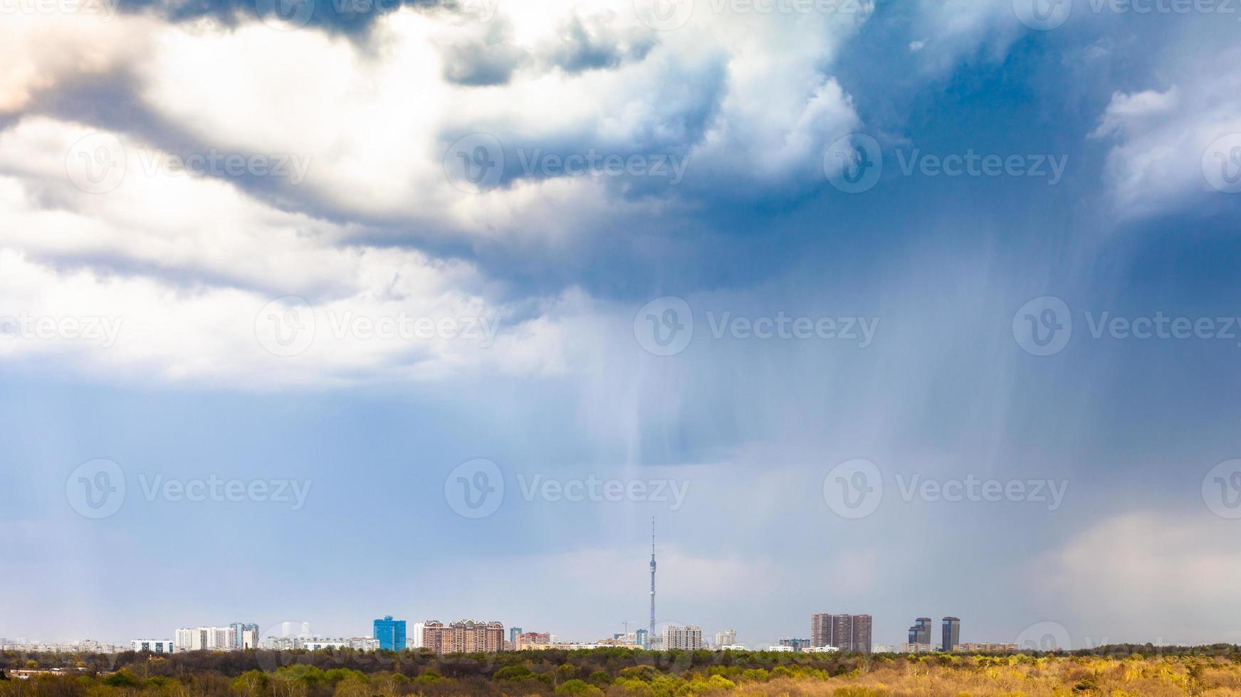 rain and rainy clouds over city and park in spring photo