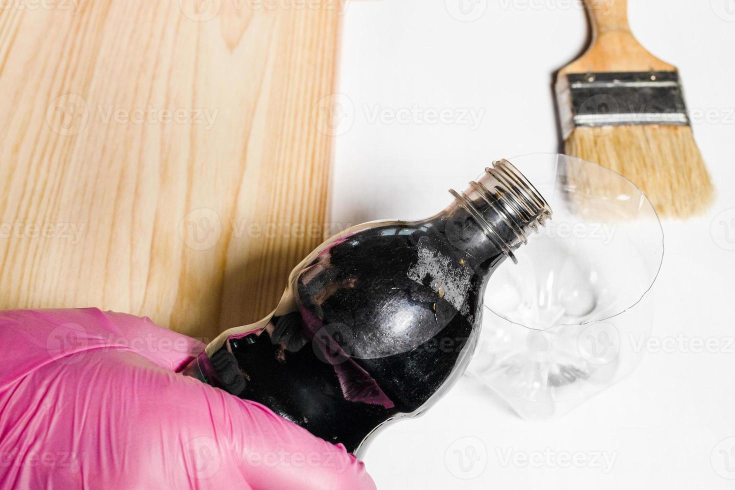 pouring wood stain from plastic bottle into jar photo