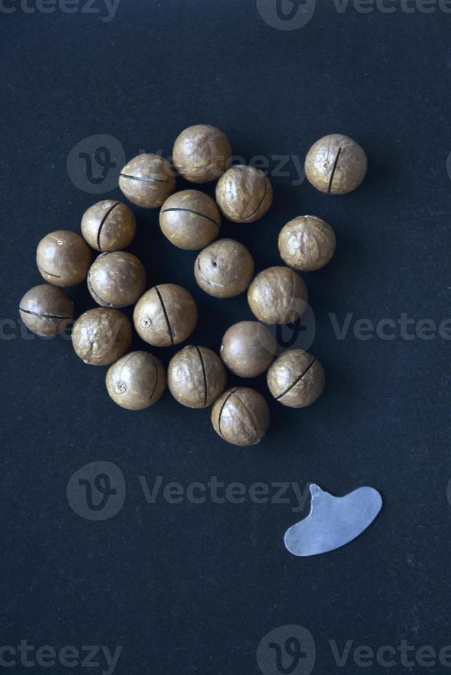 Not broken macadamia nuts on a black background in the group. photo