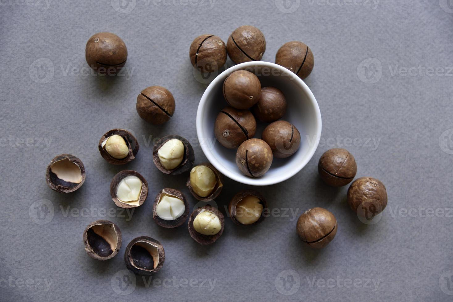 Macadamia nut in a dish with a bottle opener on a gray background. Macadamia nut prepared for use in a vase. Delicious breakfast of nuts. photo