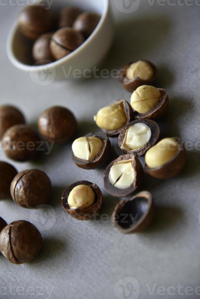 Delicious macadamia nut in a cup on a gray background. Broken nuts and shells. photo