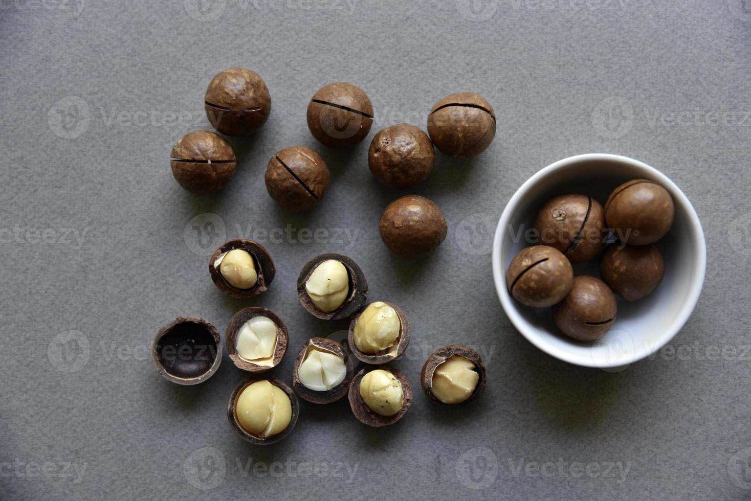 Delicious macadamia nut in a cup on a gray background. Broken nuts and shells. photo