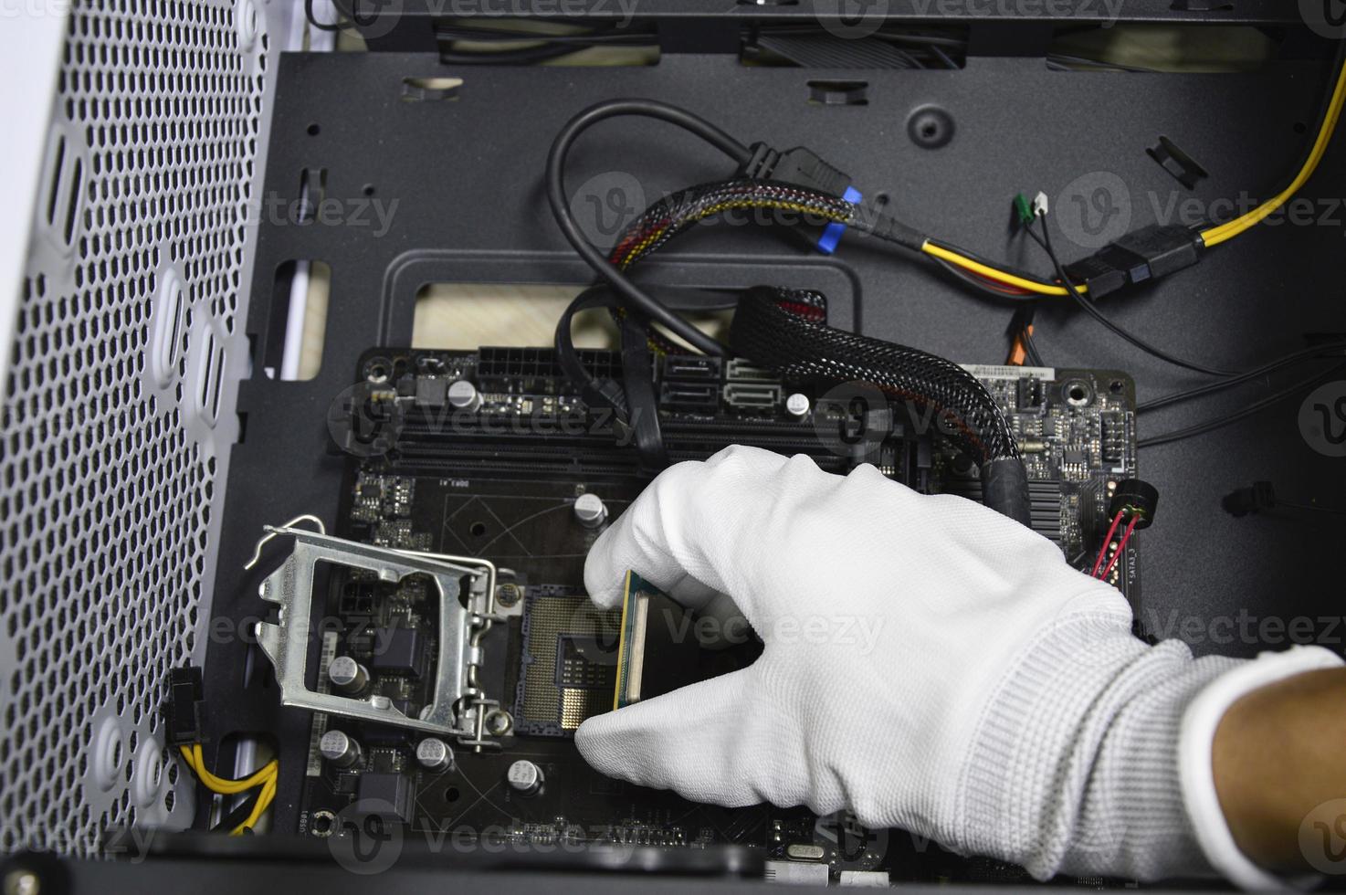 Image of a technician inserting a CPU chip onto a computer motherboard. photo