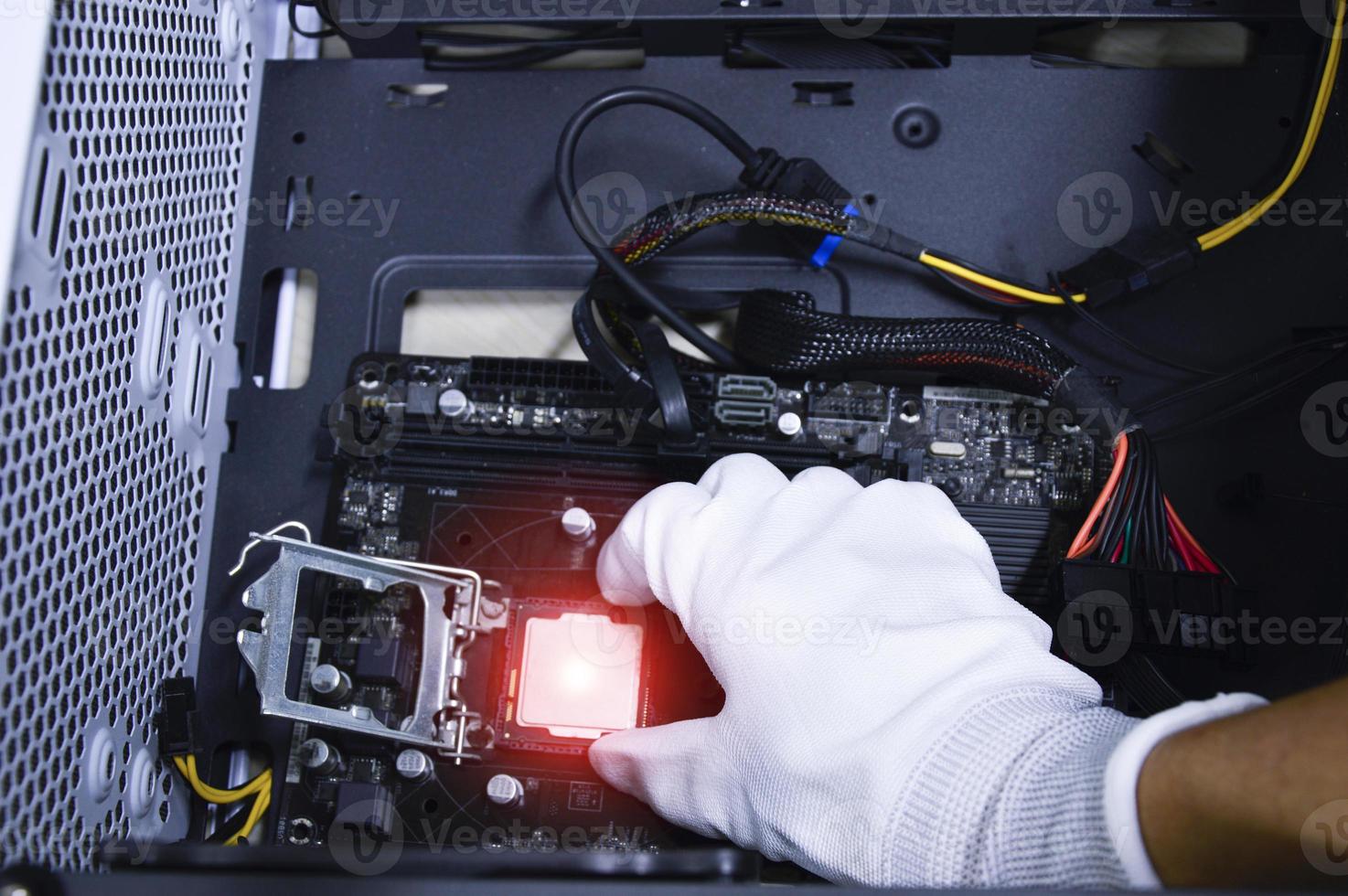 Technician is inserting a CPU chip on a computer motherboard. photo