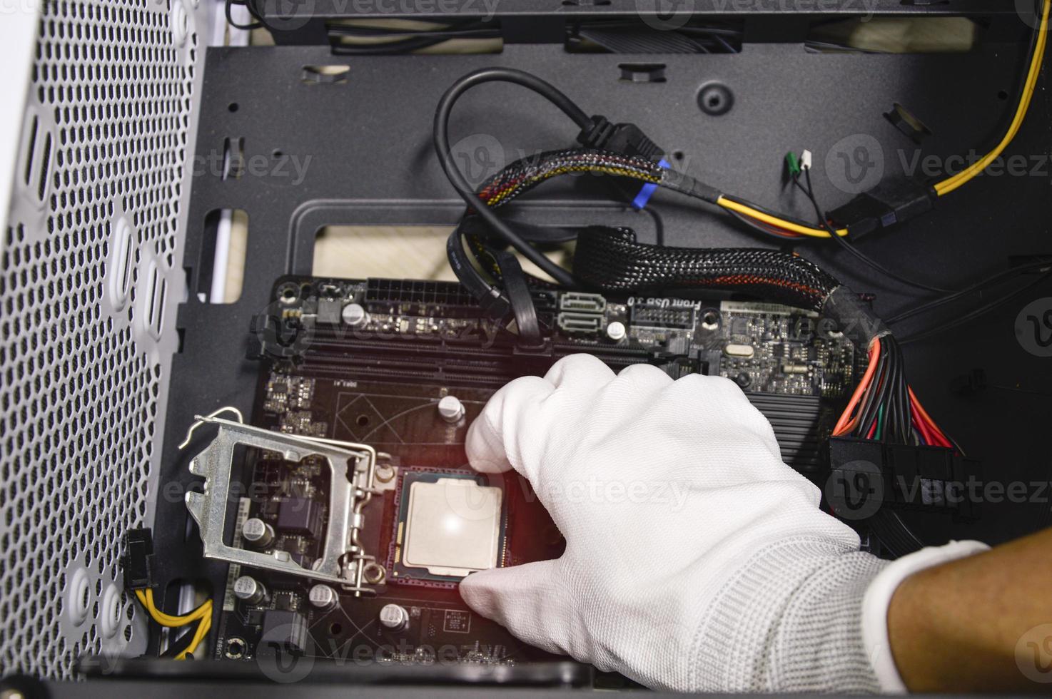 Image of a technician inserting a CPU chip onto a computer motherboard. photo