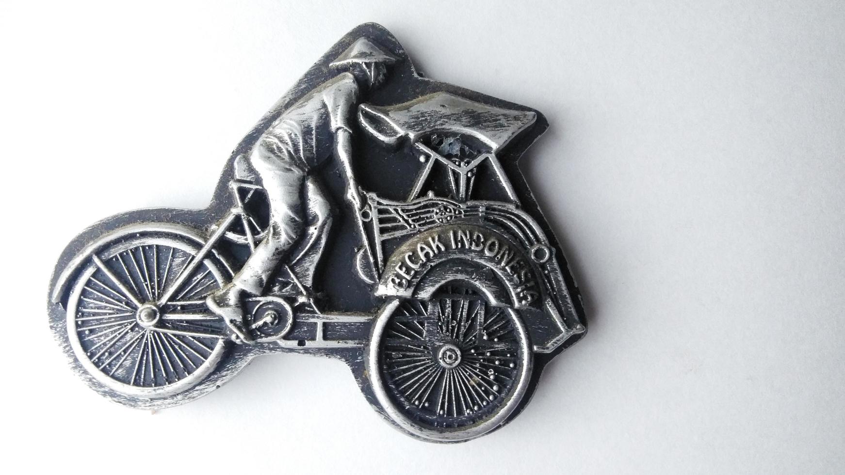 refrigerator magnet in the form of a rickshaw, pedicab is one of the means of transportation in Indonesia. fridge magnet isolated on a white background.high angle view. photo