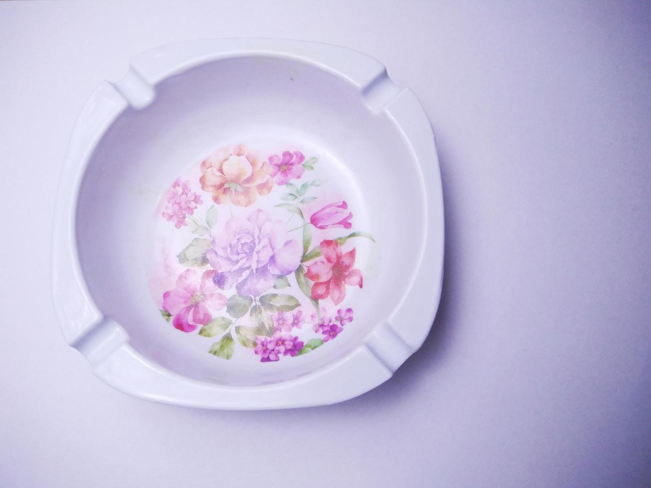 white cigarette ashtray with floral motif in the middle. ashtray isolated on a white background.  Ashtrays are often used by smokers to dispose of cigarette ashes or cigarette butts photo