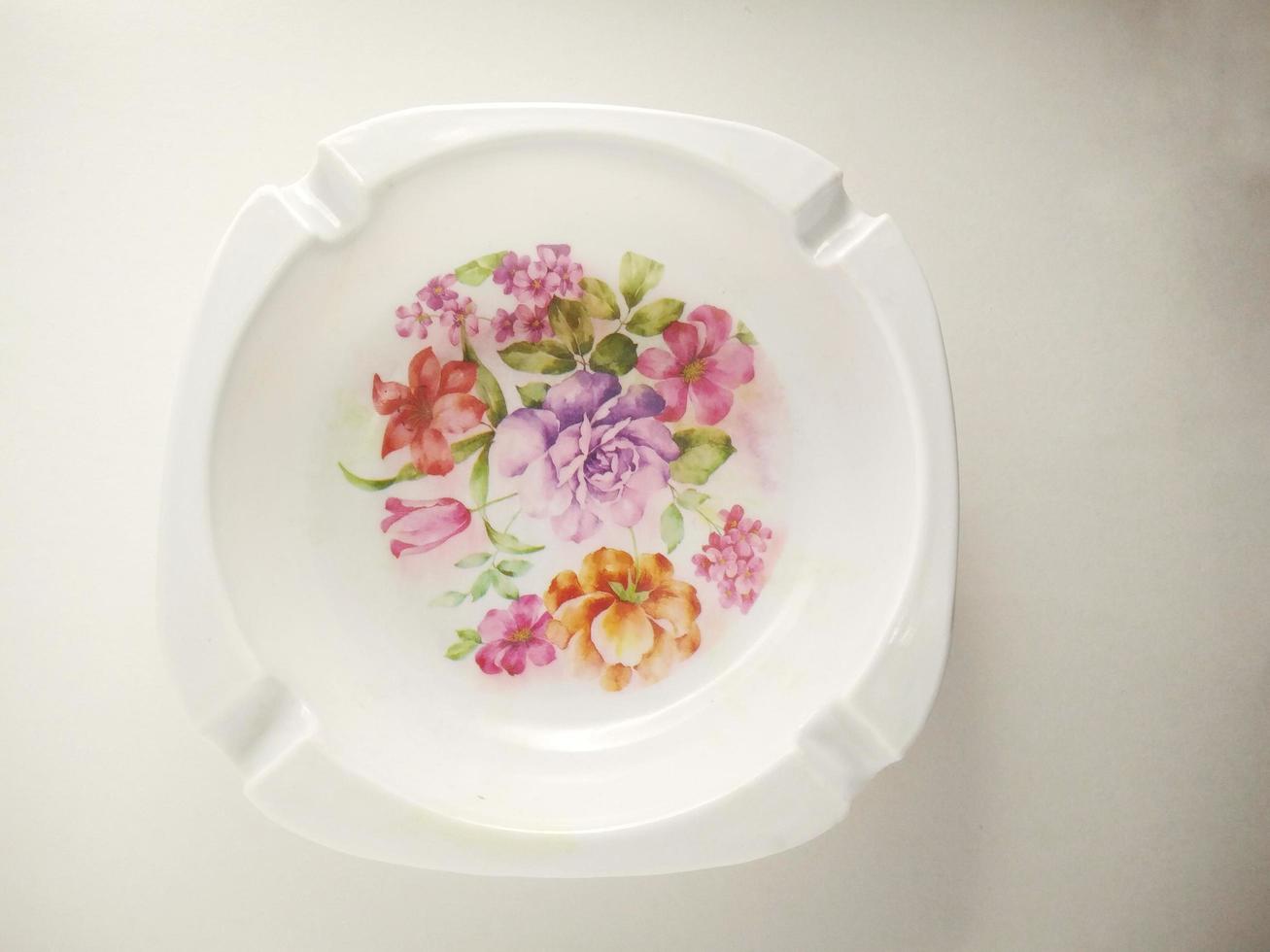 white cigarette ashtray with floral motif in the middle. ashtray isolated on a white background.  Ashtrays are often used by smokers to dispose of cigarette ashes or cigarette butts photo