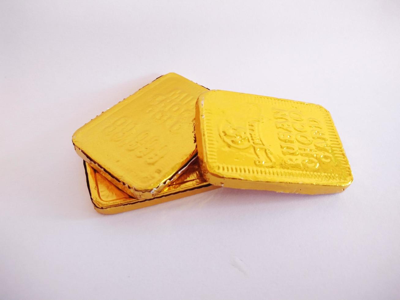 rectangular shaped chocolate wrapped in gold-colored aluminum foil.rectangular shaped chocolate isolated on a white background. photo