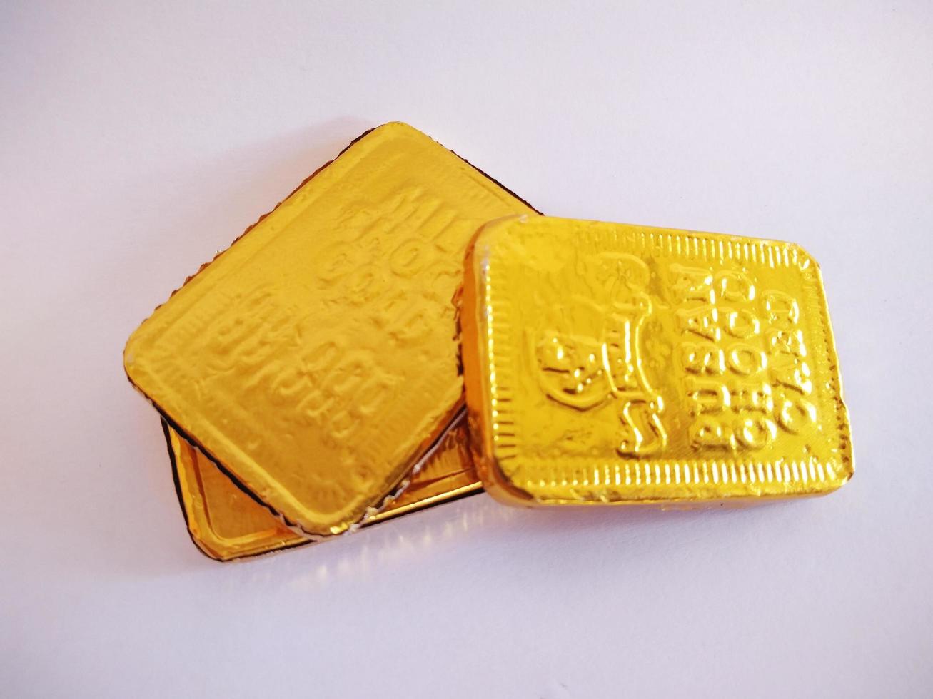 rectangular shaped chocolate wrapped in gold-colored aluminum foil.rectangular shaped chocolate isolated on a white background. photo