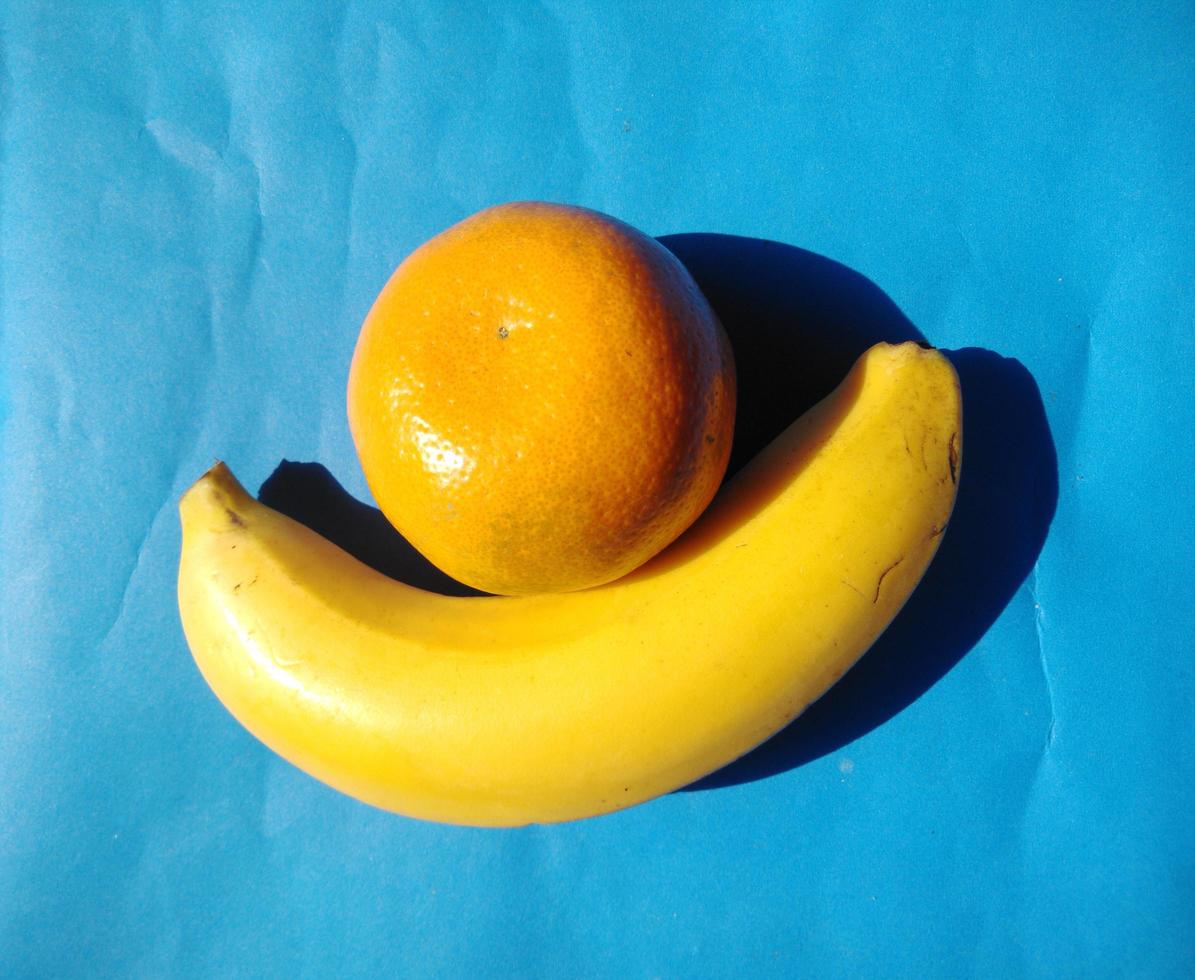 orange and banana  on a blue background.cold tone.top view. photo