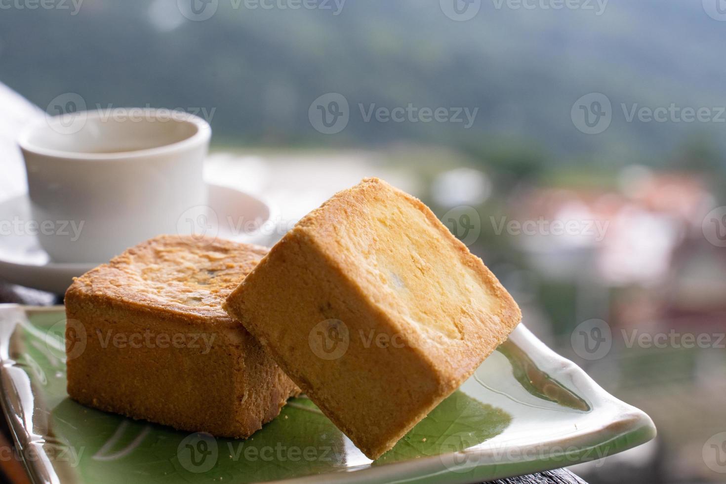 delicioso pastel de piña en un plato para el té de la tarde en una barandilla de madera de una casa de té en taiwán con un hermoso paisaje de fondo, de cerca. foto