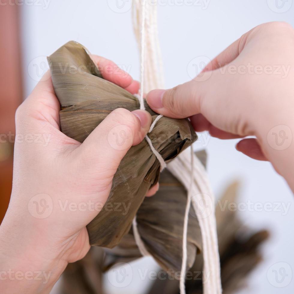 hacer bolas de arroz - envolver comida china zongzi en la mesa en casa para la celebración del festival del bote del dragón, cerrar, estilo de vida. foto