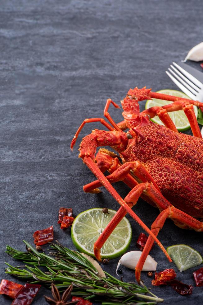 Langosta hervida cocida, deliciosa cena de marisco con cuchillo y tenedor sobre fondo de pizarra de piedra negra, diseño de menú de restaurante, primer plano, sobrecarga foto