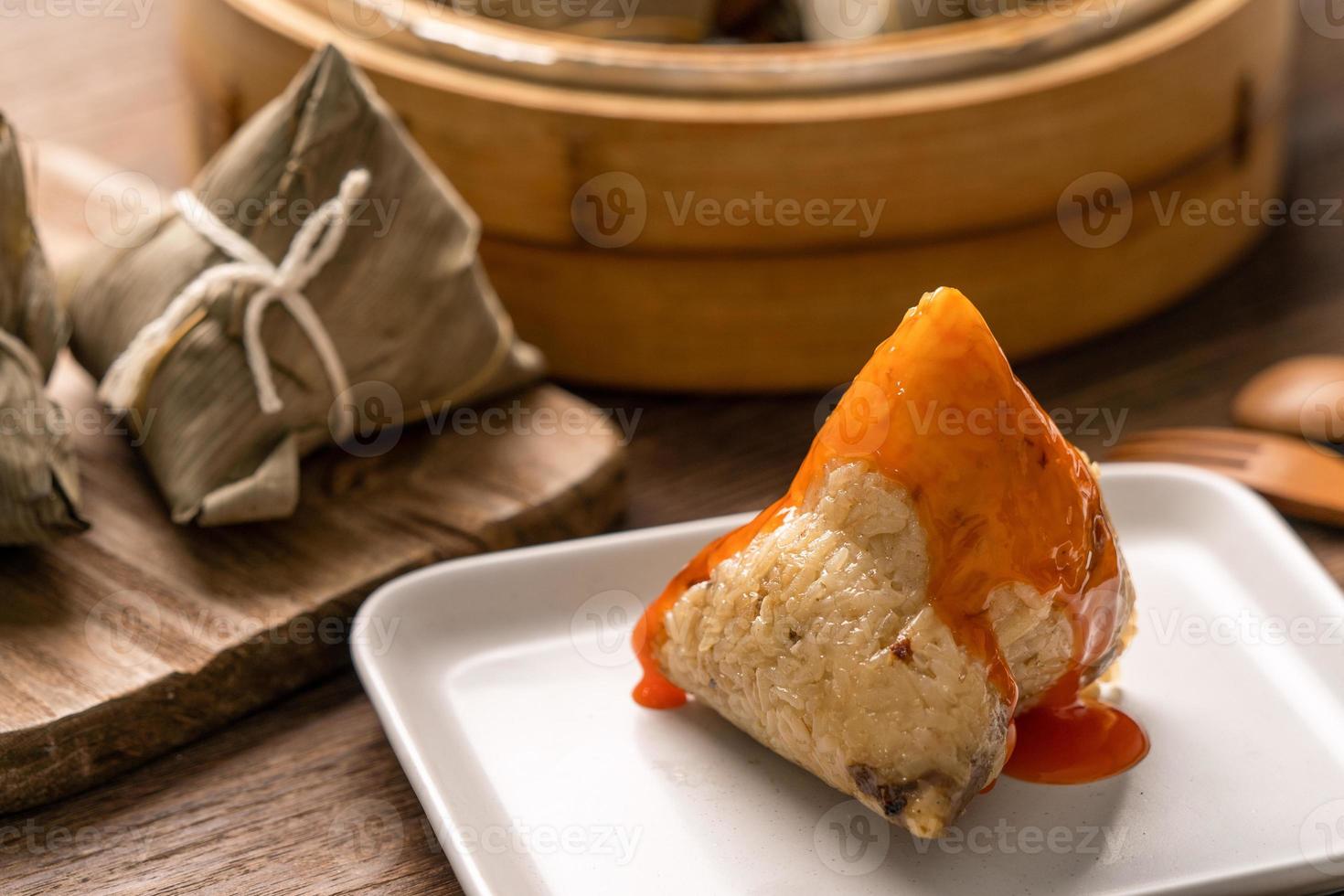 Comer zongzi - bola de arroz del festival del barco del dragón joven mujer asiática comiendo comida tradicional china en una mesa de madera en la celebración de la casa, cerrar foto