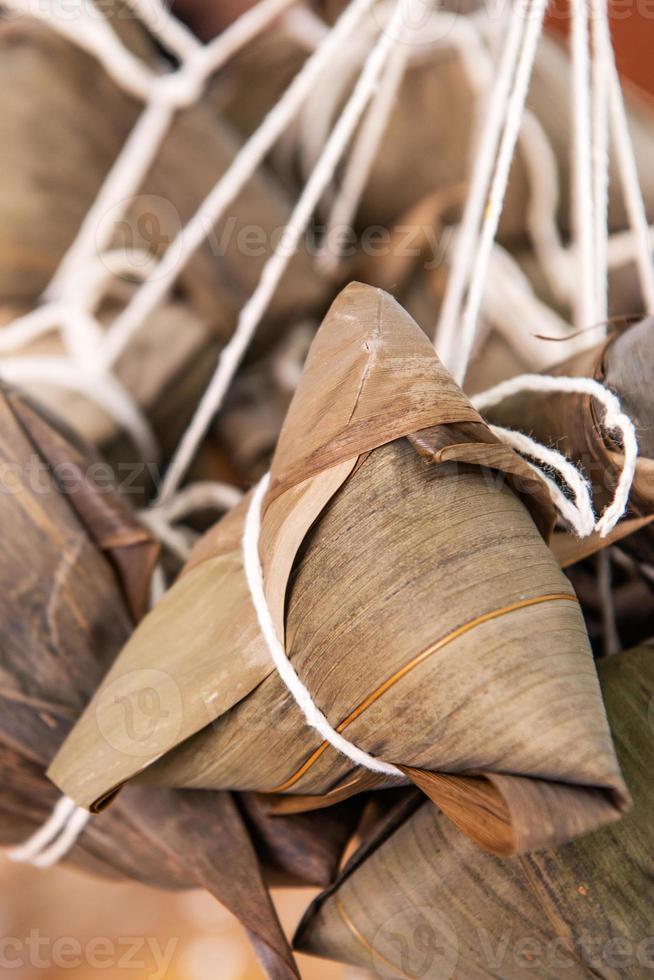 Rice dumpling zongzi making - wrapping Chinese rice dumpling zongzi on table at home for Dragon Boat Festival celebration, close up, lifestyle. photo