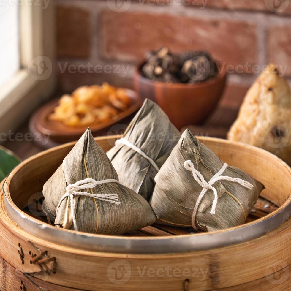 Rice dumpling, zongzi - Chinese rice dumpling zongzi in a steamer on wooden table with red brick, window background at home for Dragon Boat Festival concept, close up. photo