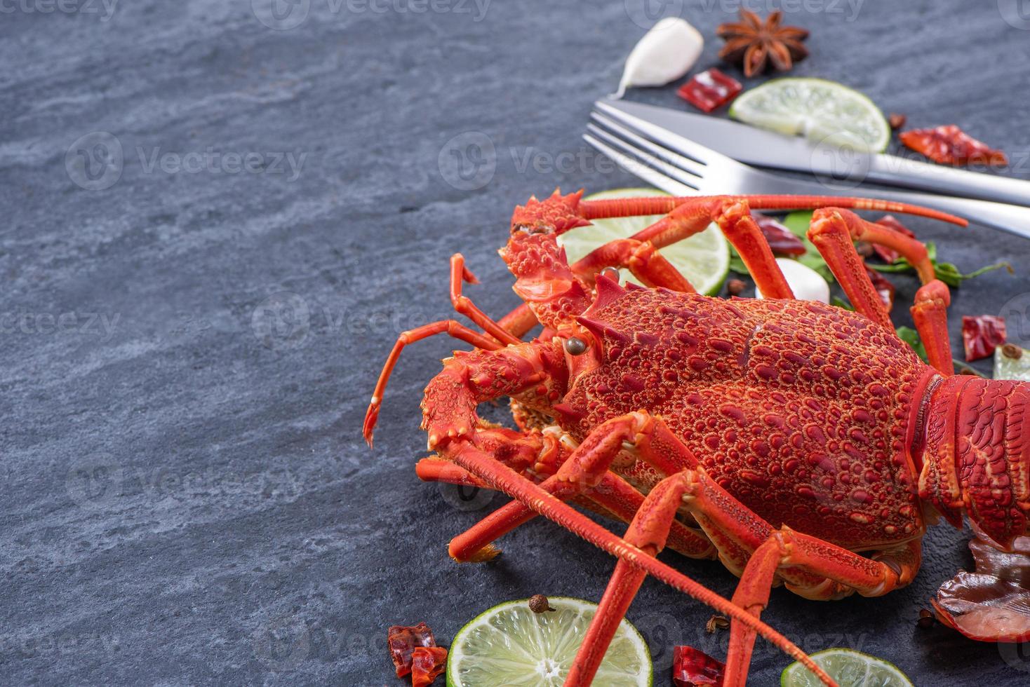 Cooked boiled lobster, delicious dinner seafood meal set with knife and fork on black stone slate background, restaurant menu design, close up, overhead photo