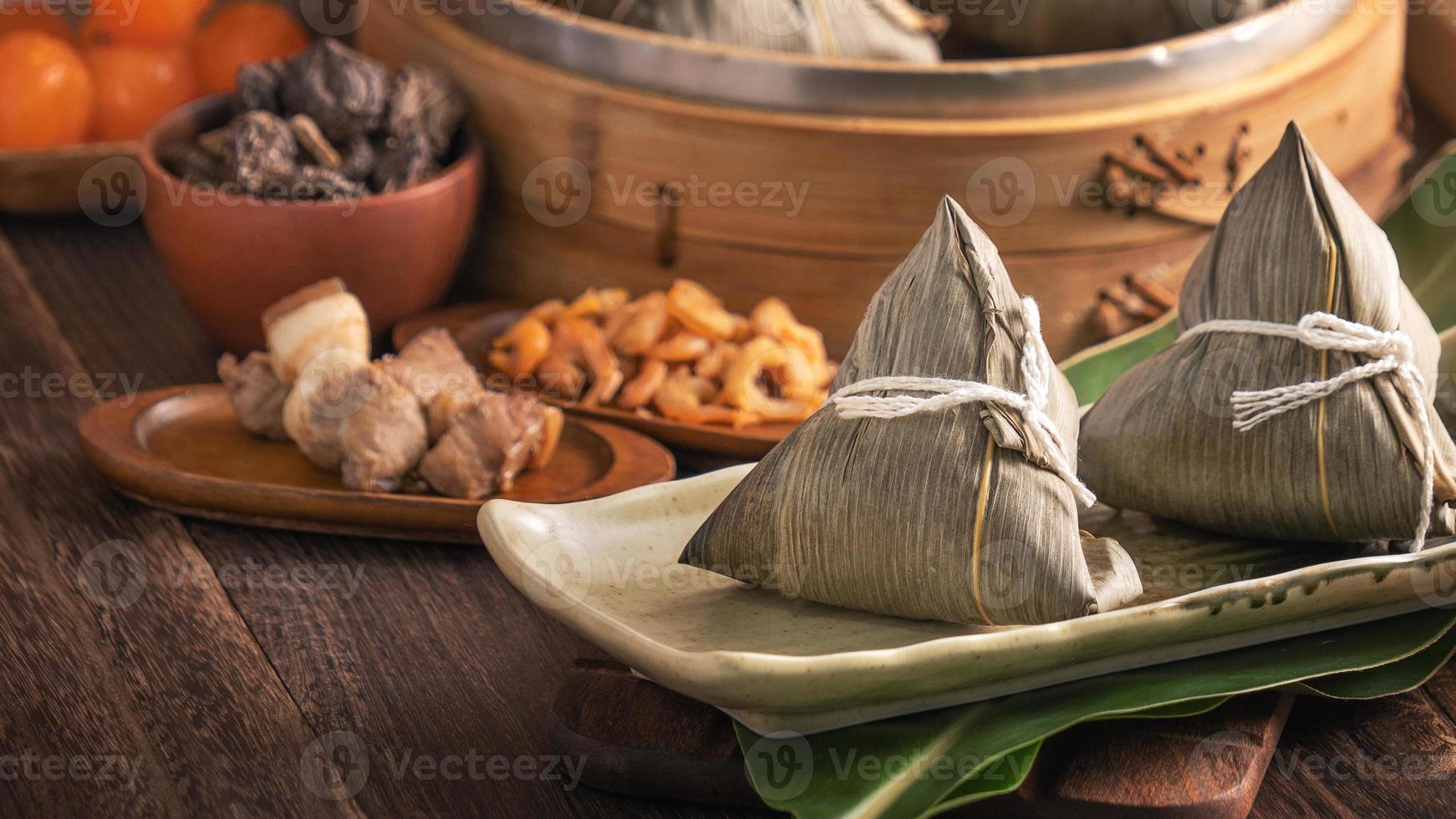 Rice dumpling - Chinese zongzi food in a steamer on wooden table with red brick wall, window background at home for Dragon Boat Festival concept, close up. photo