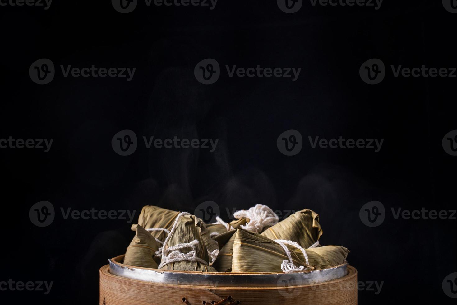 Rice dumpling, zongzi - Bunch of Chinese traditional cooked food on wooden table over black background, concept of Dragon Boat Festival, close up, copy space photo
