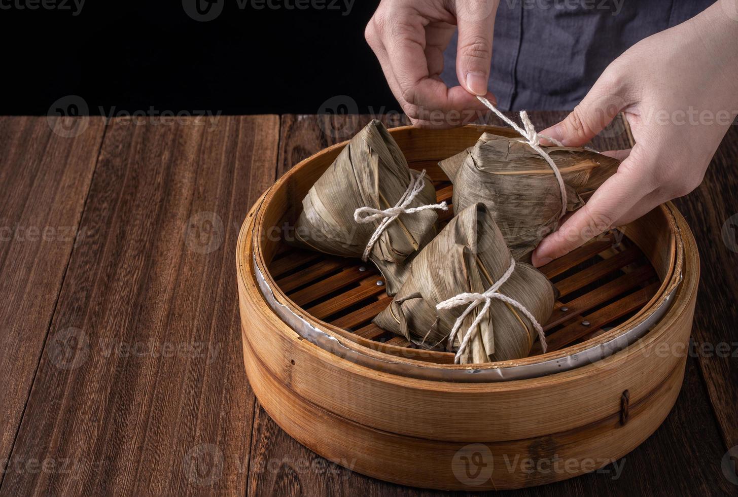 bola de arroz, zongzi - montón de comida tradicional china cocinada en una mesa de madera sobre fondo negro, concepto de festival de botes de dragón, primer plano, espacio de copia foto