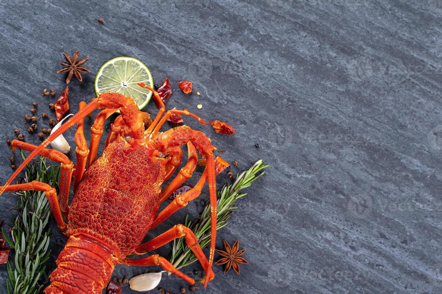Cooked boiled lobster, delicious dinner seafood meal set with knife and fork on black stone slate background, restaurant menu design, top view, overhead photo