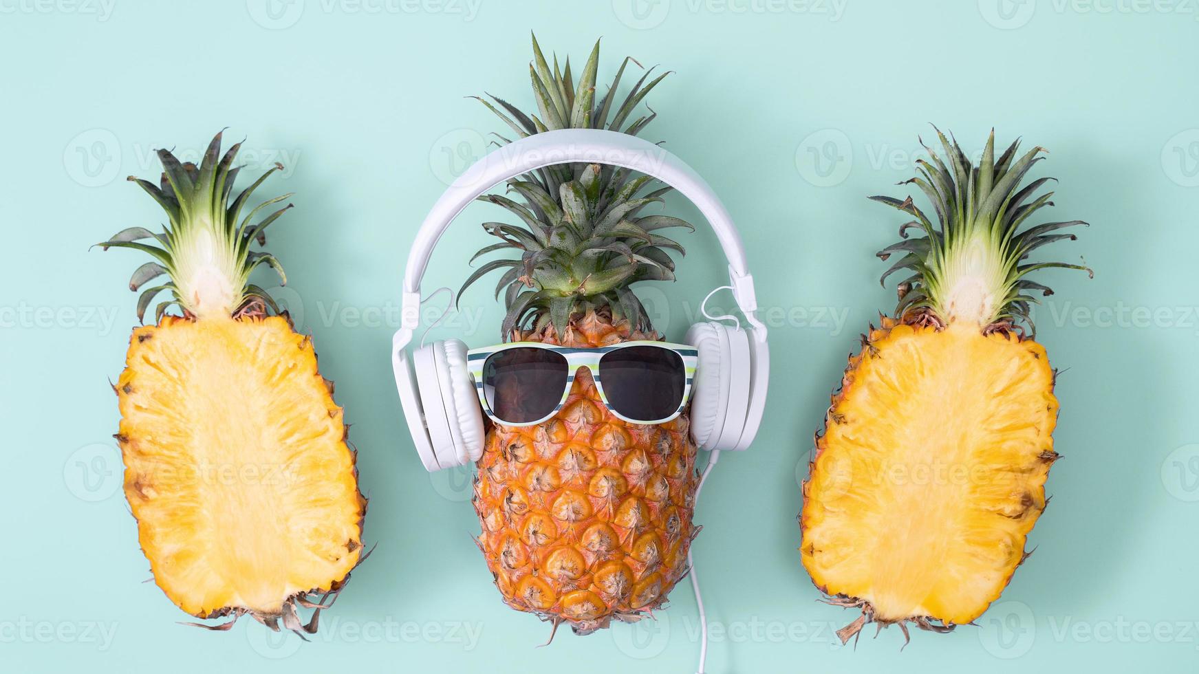 piña divertida con auriculares blancos, concepto de escuchar música, aislada en un fondo de color con hojas de palma tropical, vista superior, diseño plano. foto