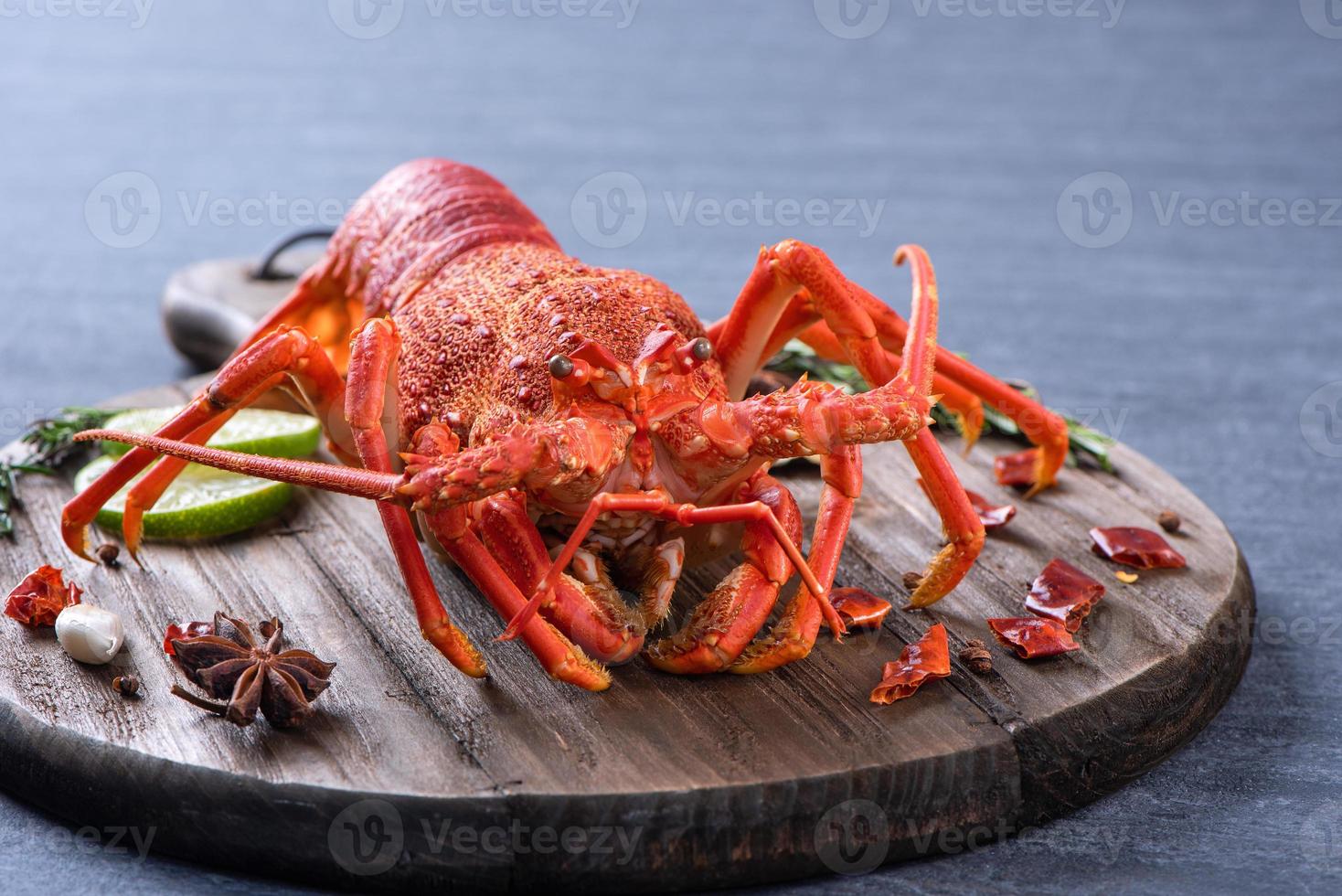 Cooked boiled lobster, delicious dinner seafood meal set with knife and fork on black stone slate background, restaurant menu design, close up, overhead photo