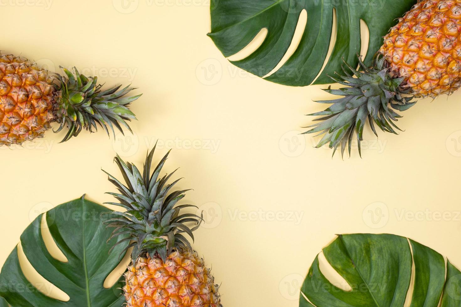 Beautiful pineapple on tropical palm monstera leaves isolated on bright pastel yellow background, top view, flat lay, overhead above summer fruit. photo