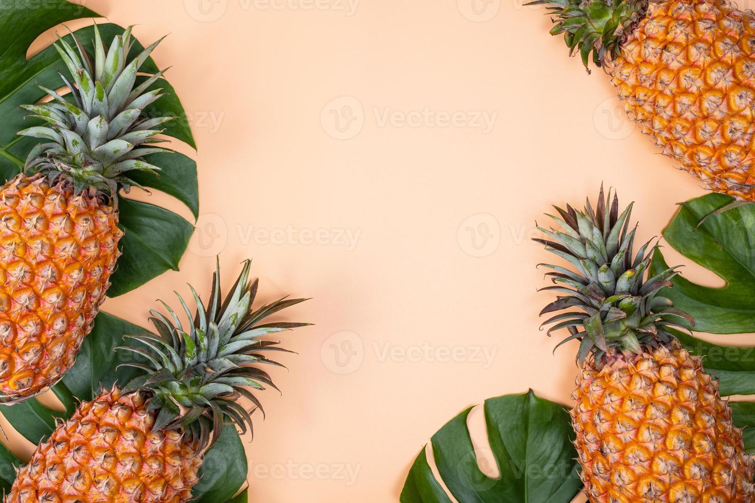 Beautiful pineapple on tropical palm monstera leaves isolated on bright pastel orange yellow background, top view, flat lay, overhead above summer fruit. photo