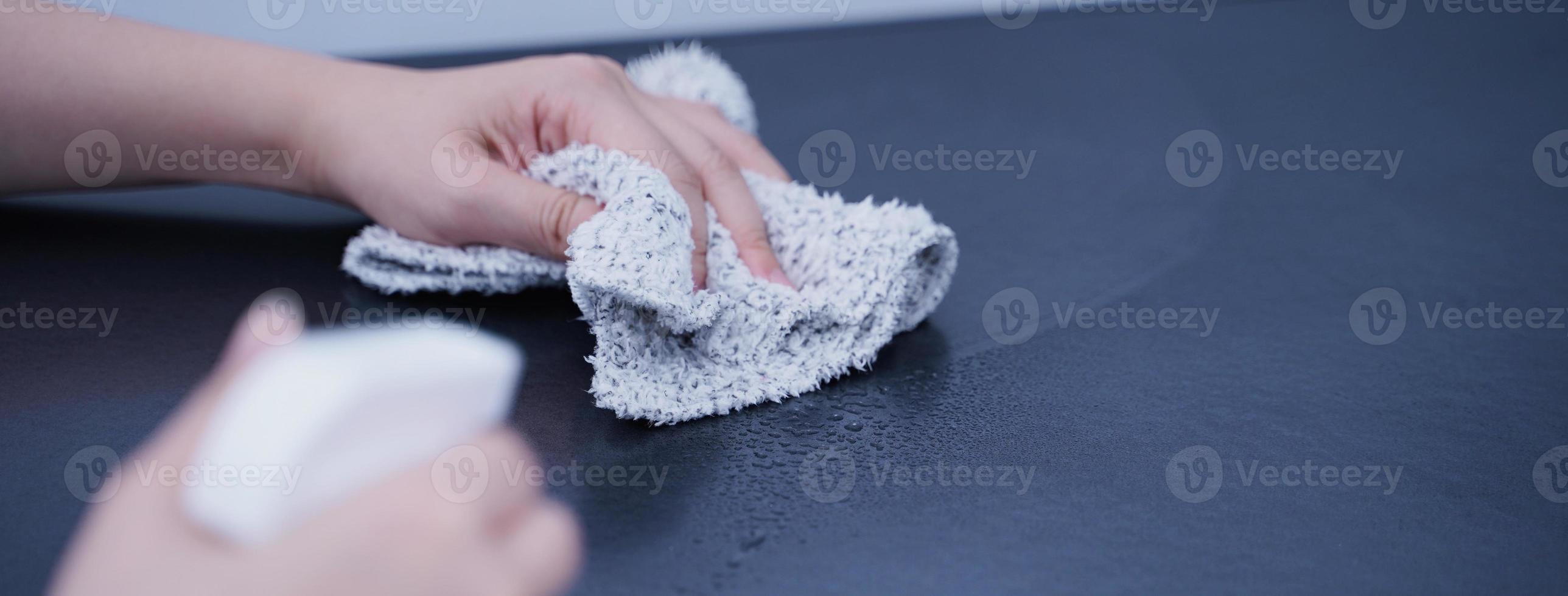 la mujer joven está sosteniendo una botella de spray, un trapo para limpiar, limpiar la superficie de alojamiento del estante del gabinete de metal de la oficina, cerrar, estilo de vida, concepto de antibacteriano. foto