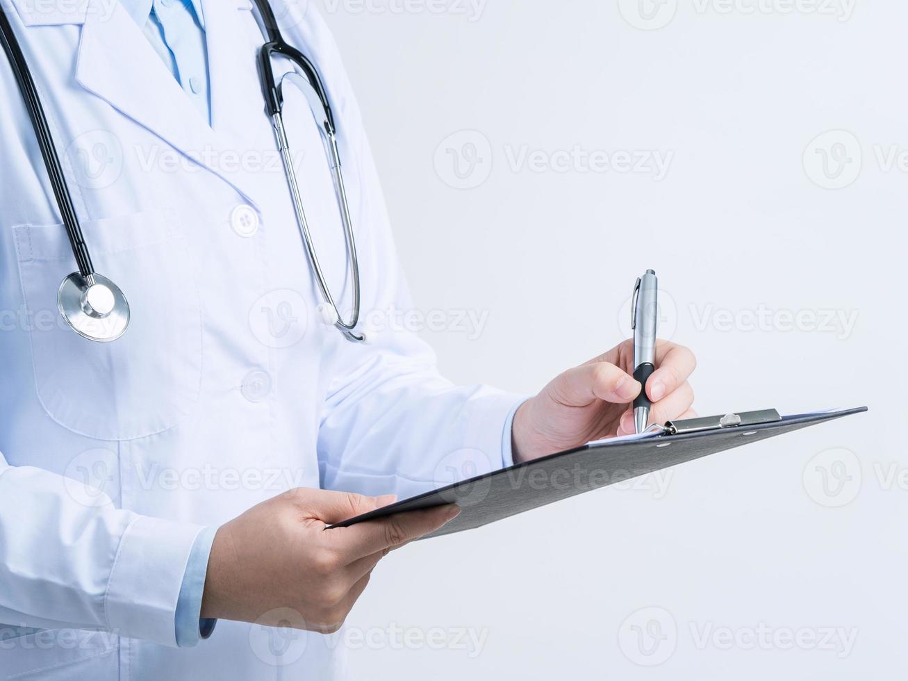 Doctor with stethoscope in white coat holding clipboard, writing medical record diagnosis, isolated on white background, close up, cropped view. photo