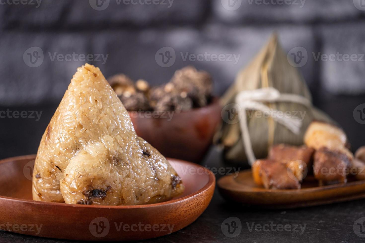 dumpling de arroz, zongzi - dumpling de arroz chino zongzi sobre una mesa de pizarra de fondo de ladrillo negro, concepto de comida tradicional del festival del barco del dragón, de cerca. foto