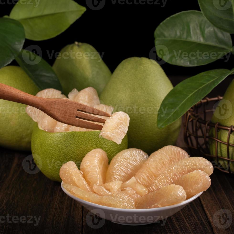 Fresh pomelo, pummelo, grapefruit, shaddock on wooden table over black background, close up, copy space. Fruit for Mid-autumn festival. photo