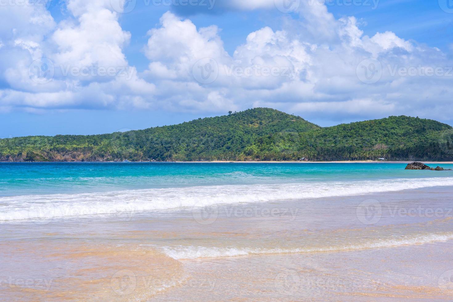 Beautiful amazing gold colored sandy beach with soft waves isolated with sunny blue sky. Concept of tropical calm tourism idea, copy space, close up photo