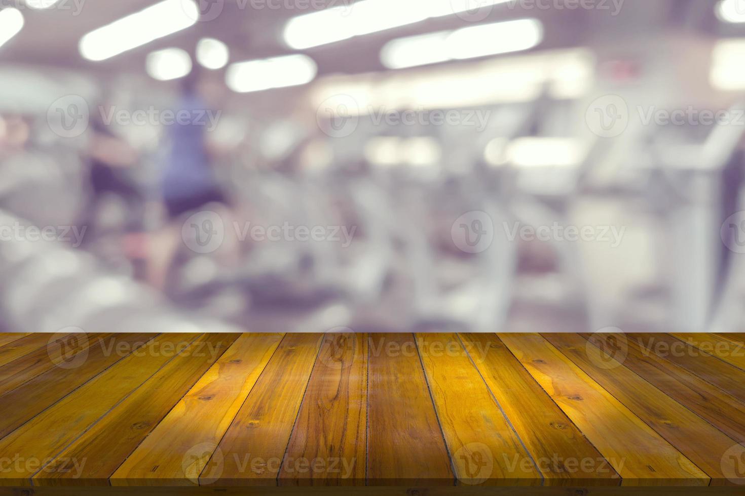 Empty wooden board space platform with blur fitness gym equipment background photo