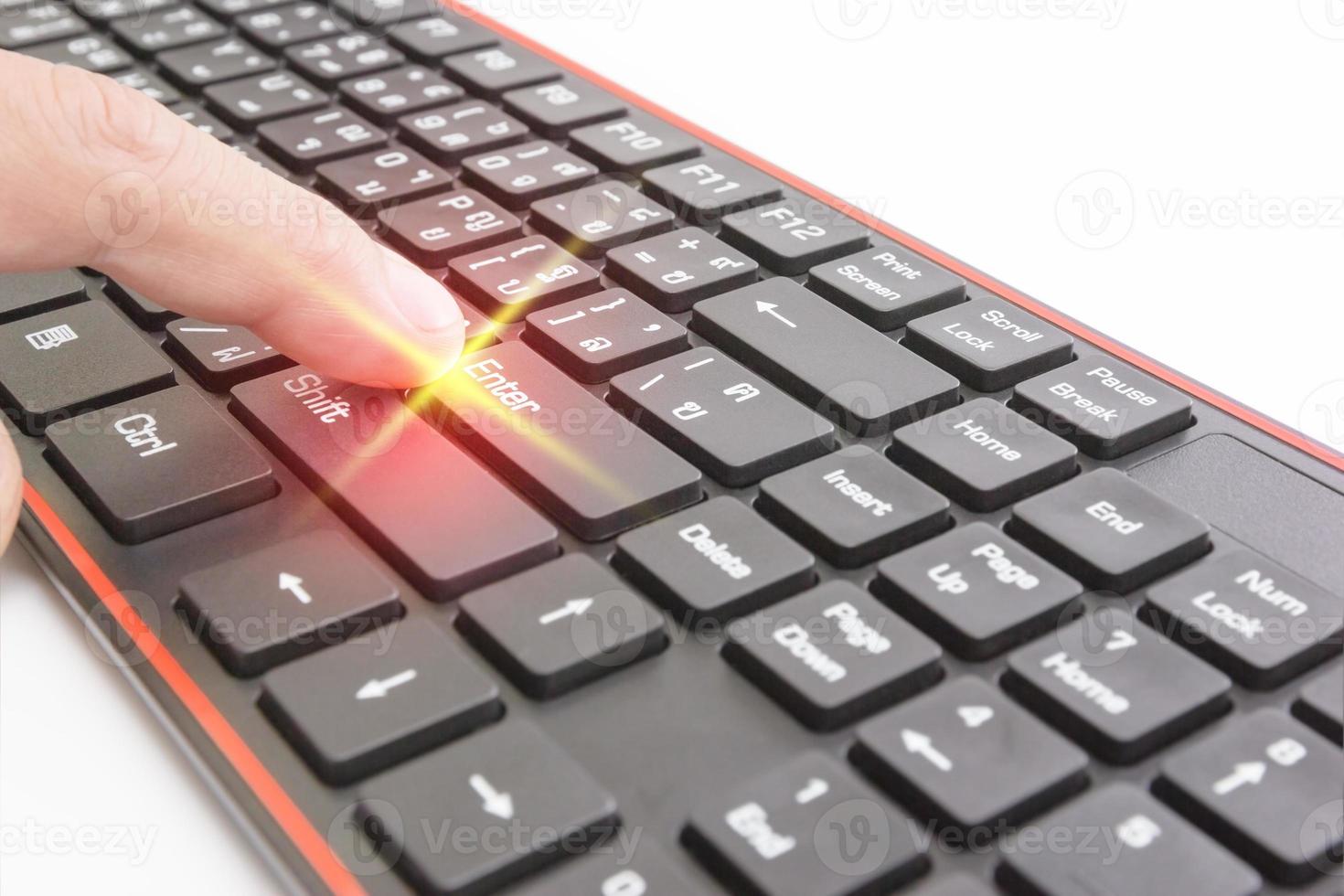 Finger pushing enter button on black keyboard,light effect photo