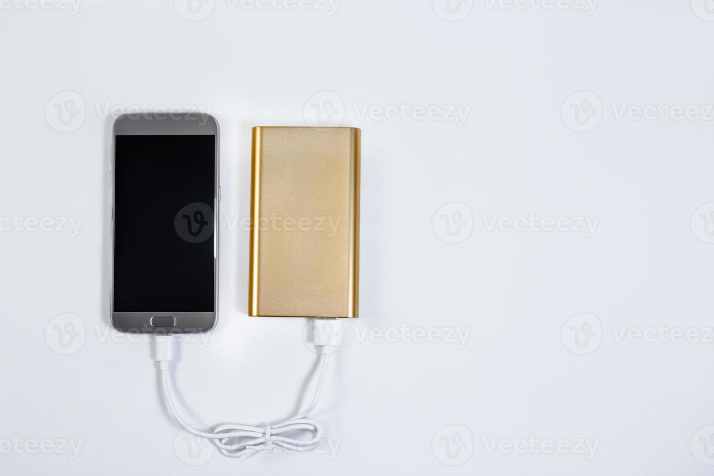 Golden powerbank with smart phone on background photo