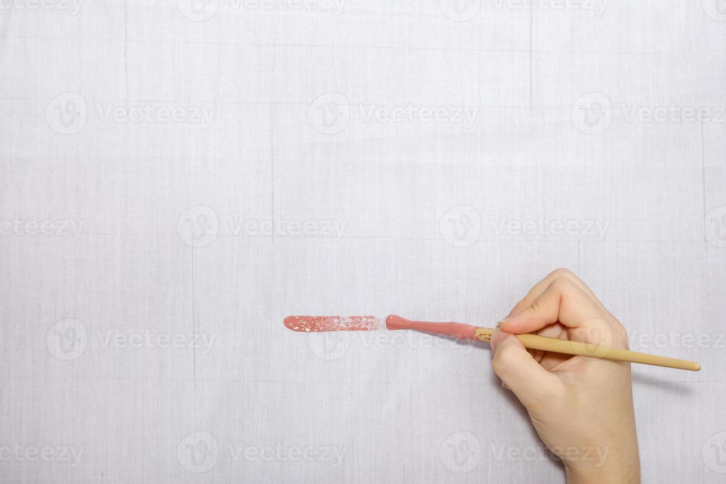 hand holding paintbrush paint on gray cloth photo